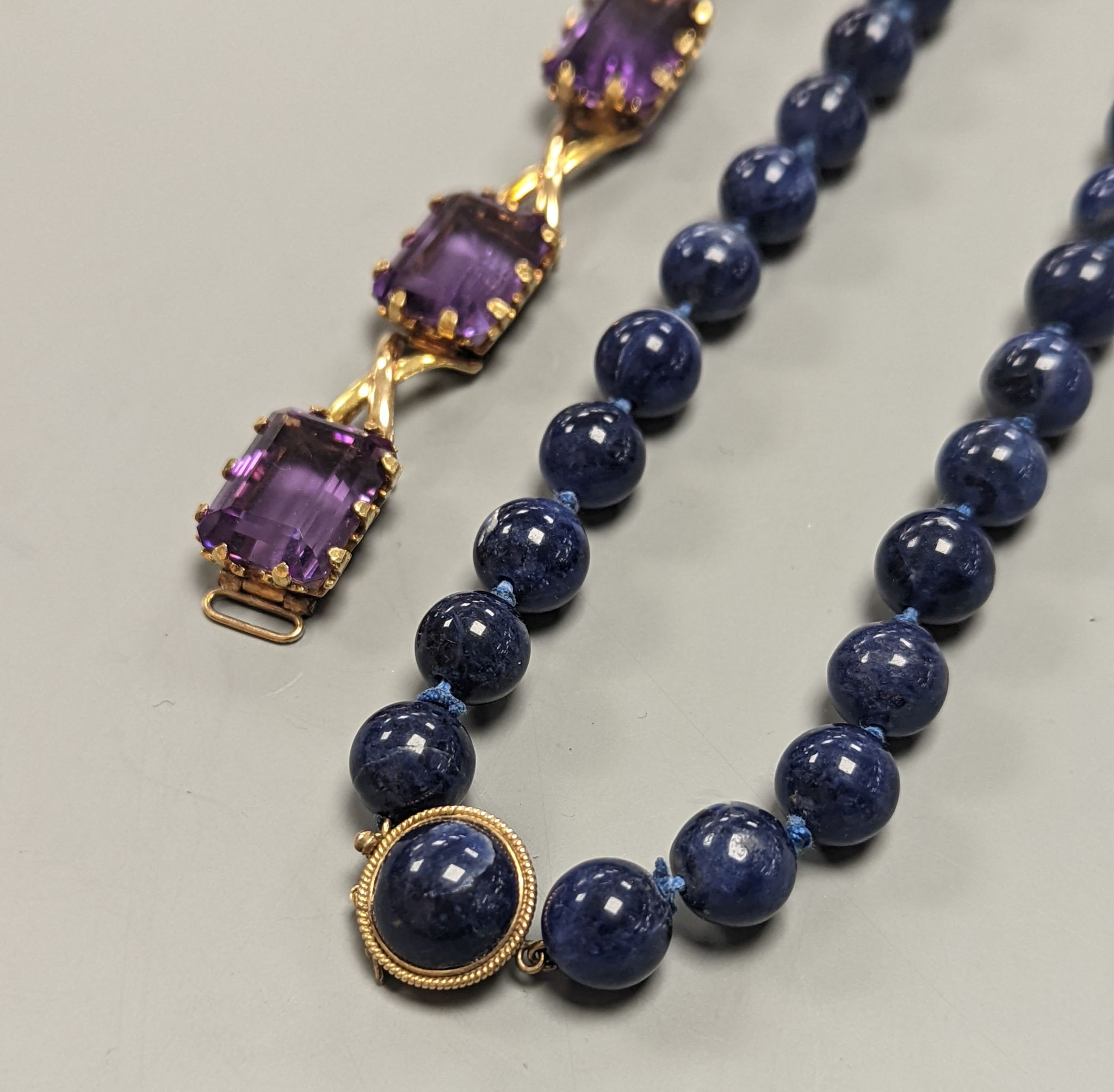 A yellow metal and six stone emerald cut amethyst set part bracelet(a.f.), 17.1cm and a modern single strand lapis lazuli bead necklace with 14k yellow metal clasp.